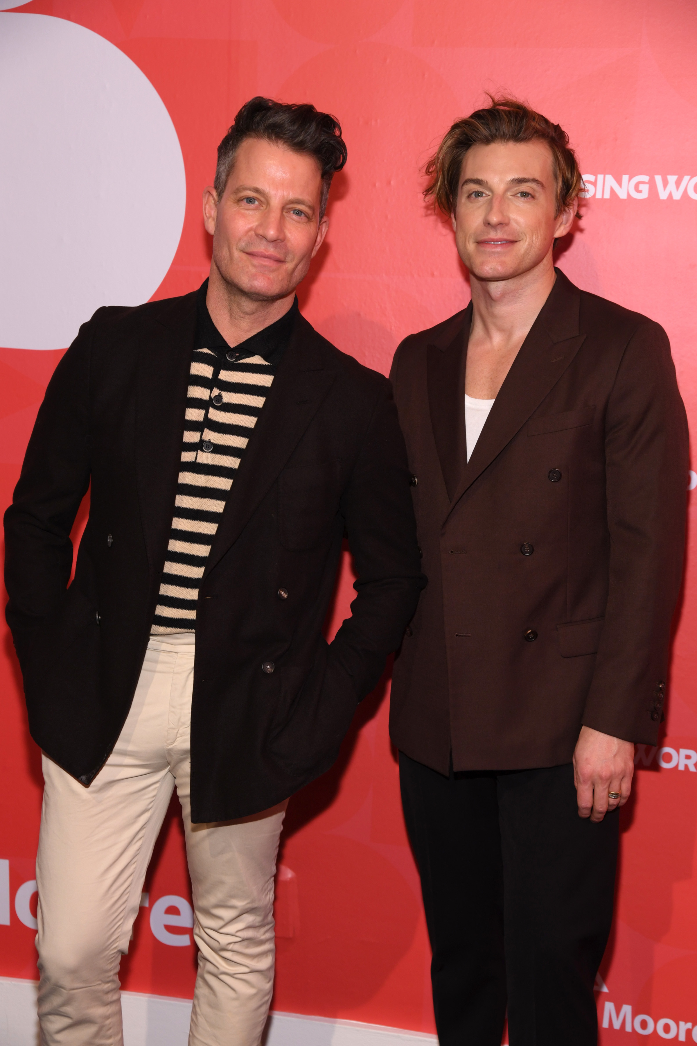 Nate and Jeremiah posing, one in a striped shirt and jacket, the other in a suit, on the red carpet