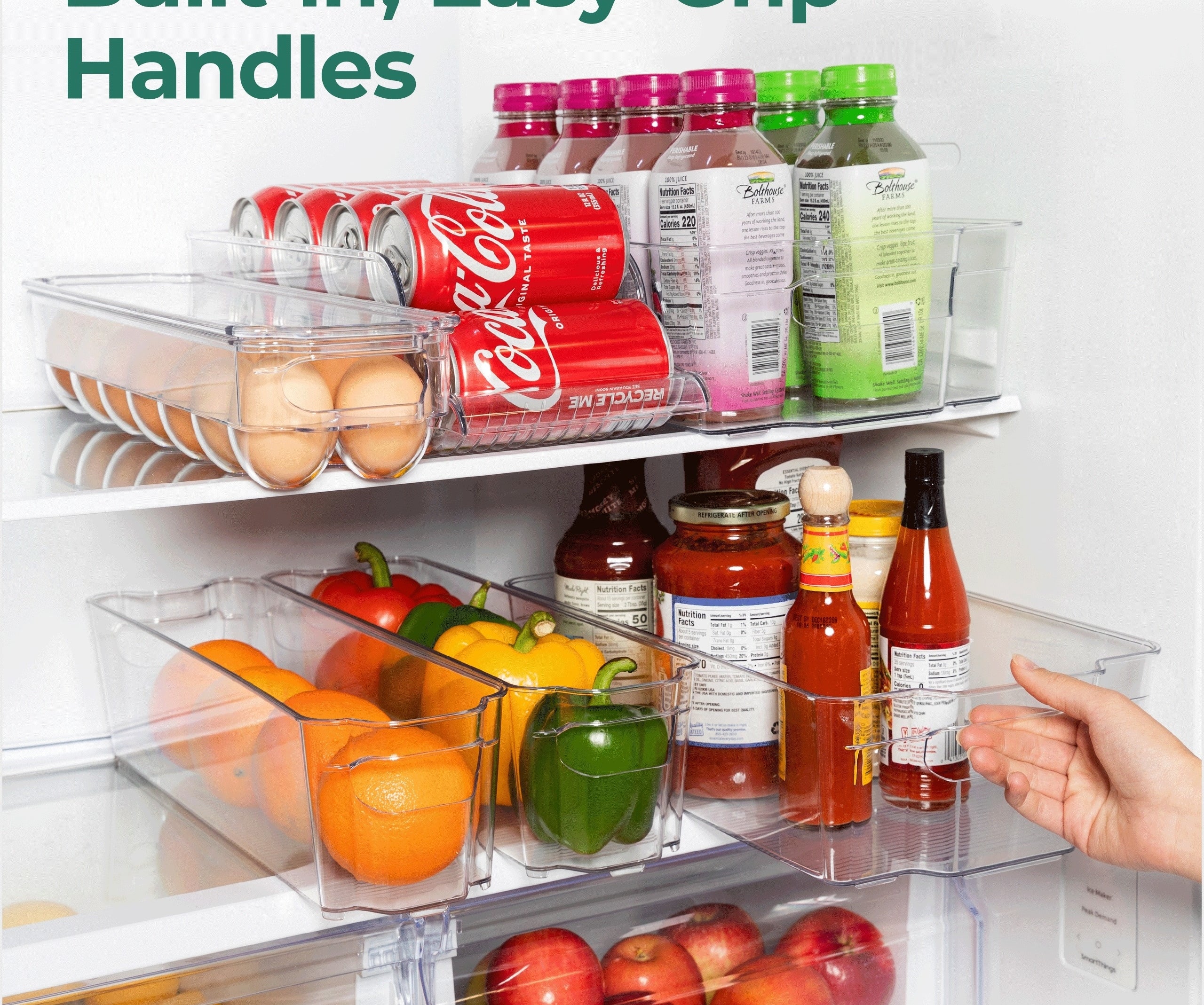 A hand opening a clear fridge drawer full of various fruits and organized groceries