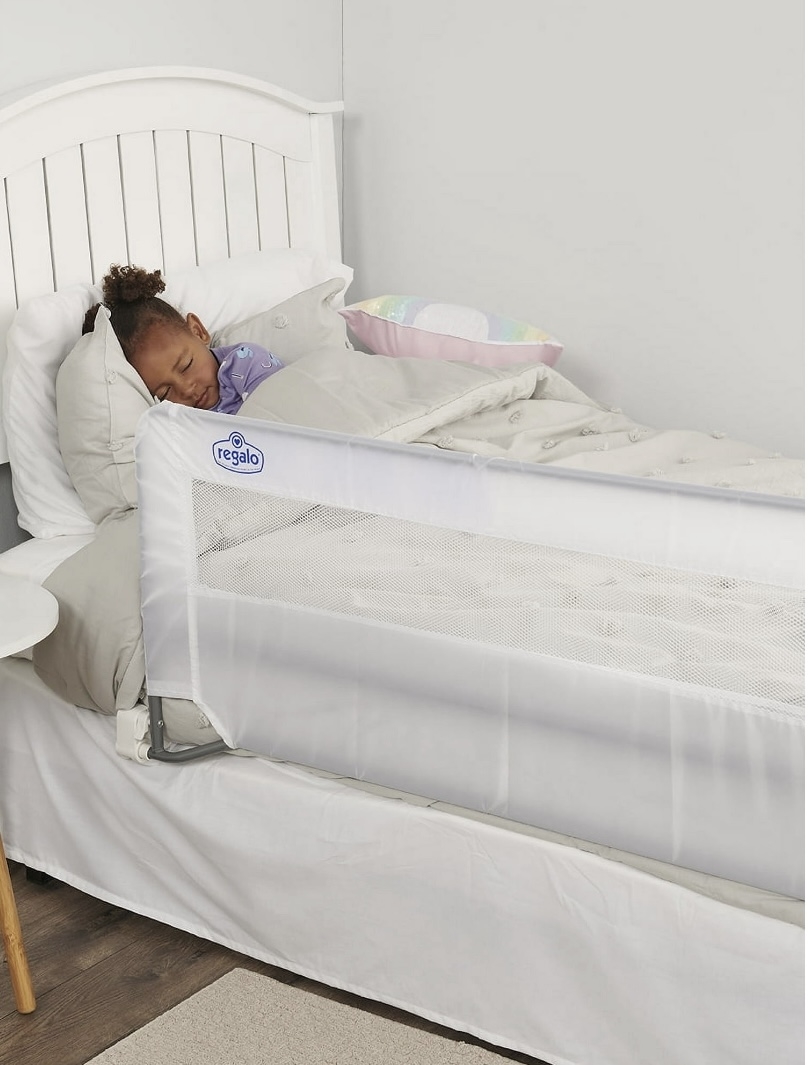 Toddler sleeping in bed with a white mesh safety bedrail installed on the side