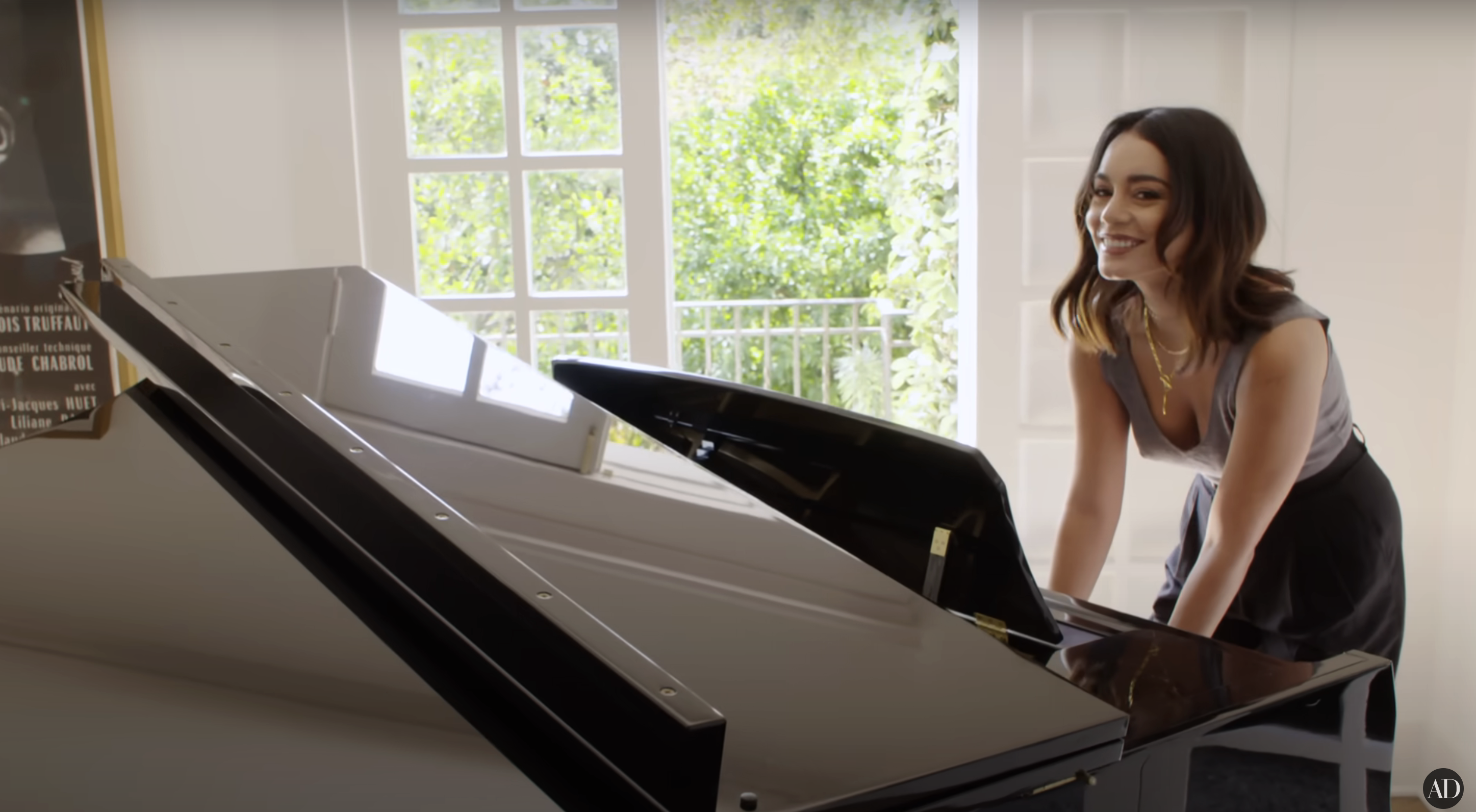Vanessa smiling at piano, sheet music on stand, bright room with window