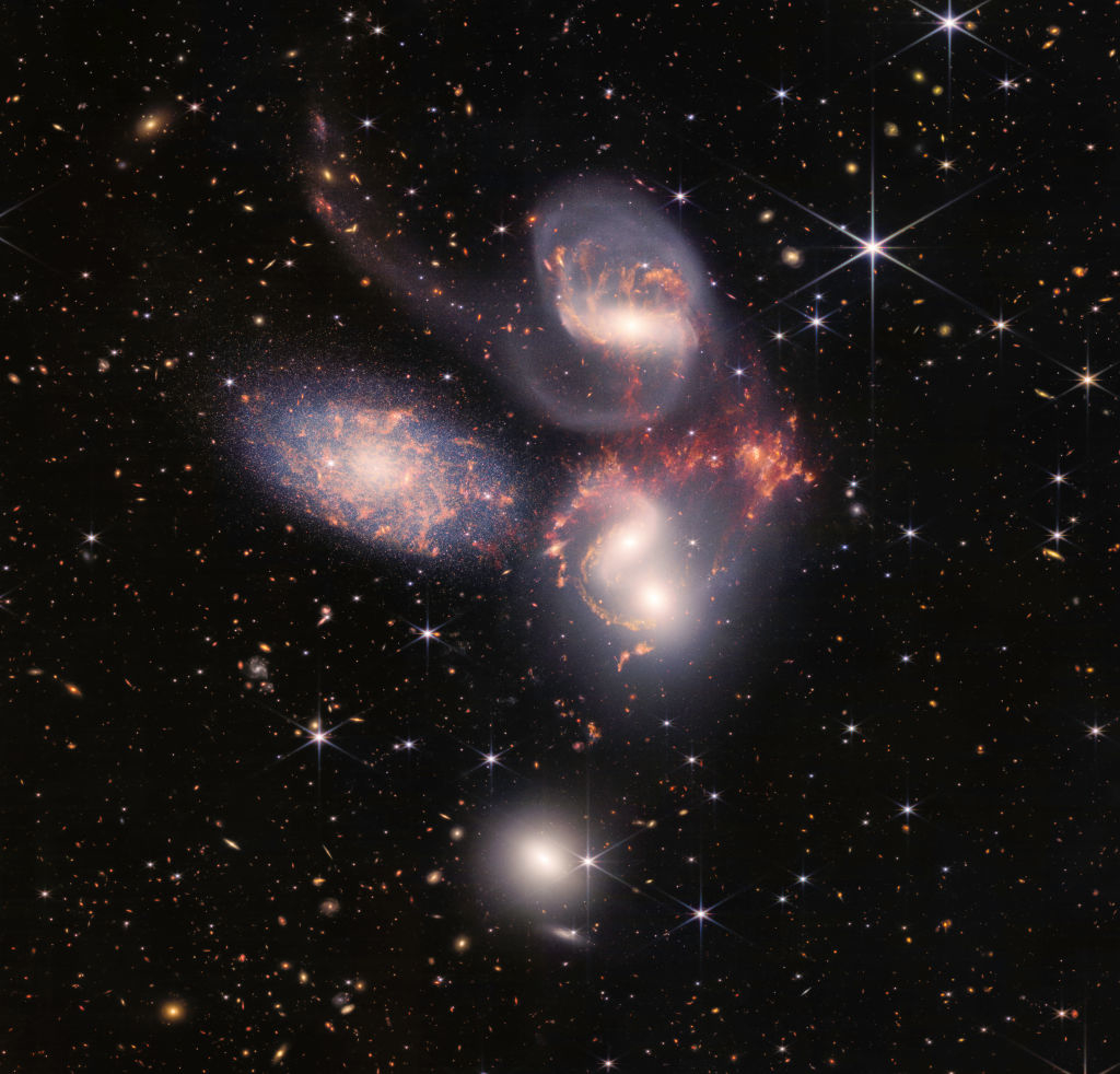 A vivid image of a cosmic scene with multiple galaxies and star clusters against a dark sky