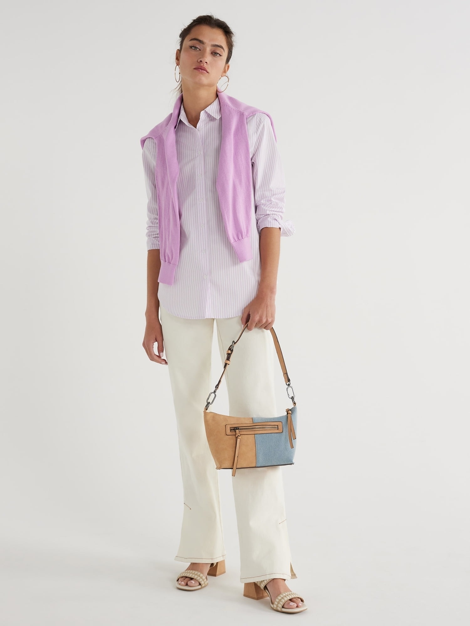 Model in a pink striped shirt, cream pants, holding a two-tone handbag