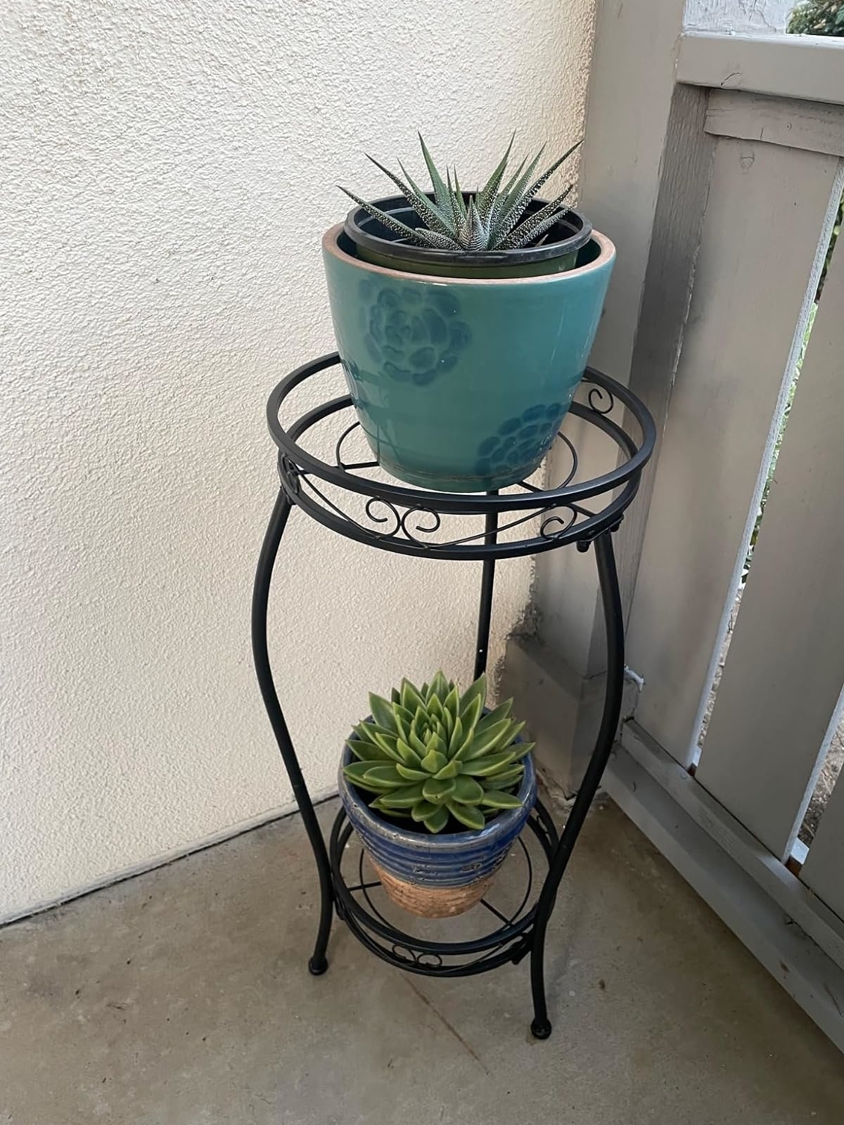 Two potted succulent plants on a tiered metal stand on a patio