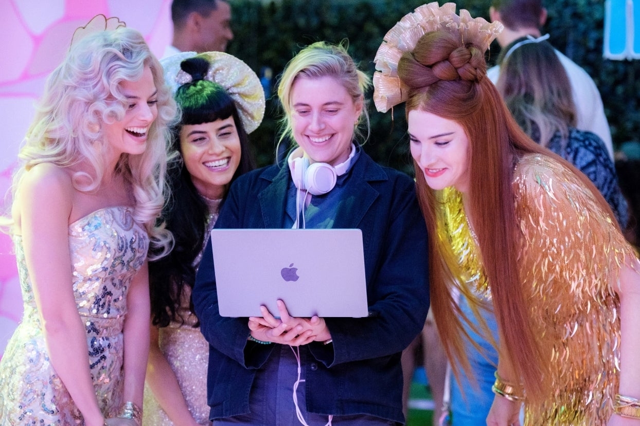 Four people in vibrant costumes smiling at a laptop screen