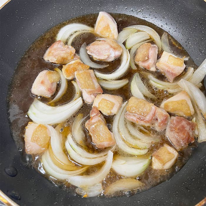 鍋に玉ねぎと鶏肉が炒められている途中の料理の様子です。