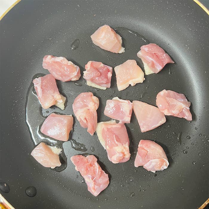 フライパンで調理される生の鶏肉の小片