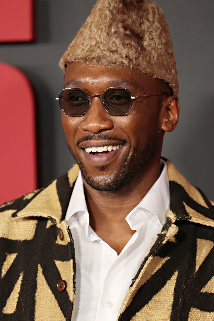 Man in patterned coat and fur hat smiling at an event