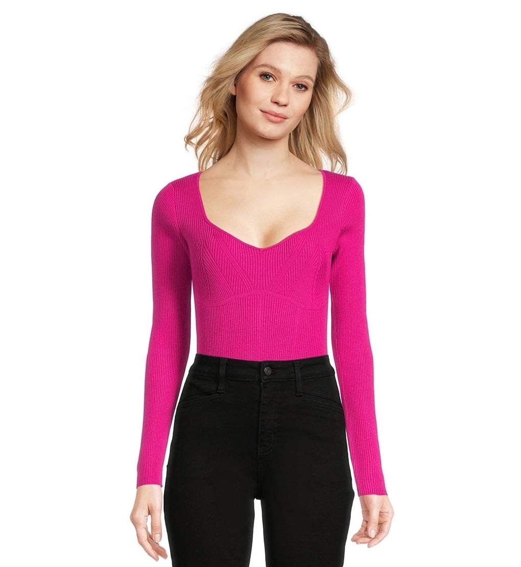 model posing in a pink, knit bodysuit and black pants