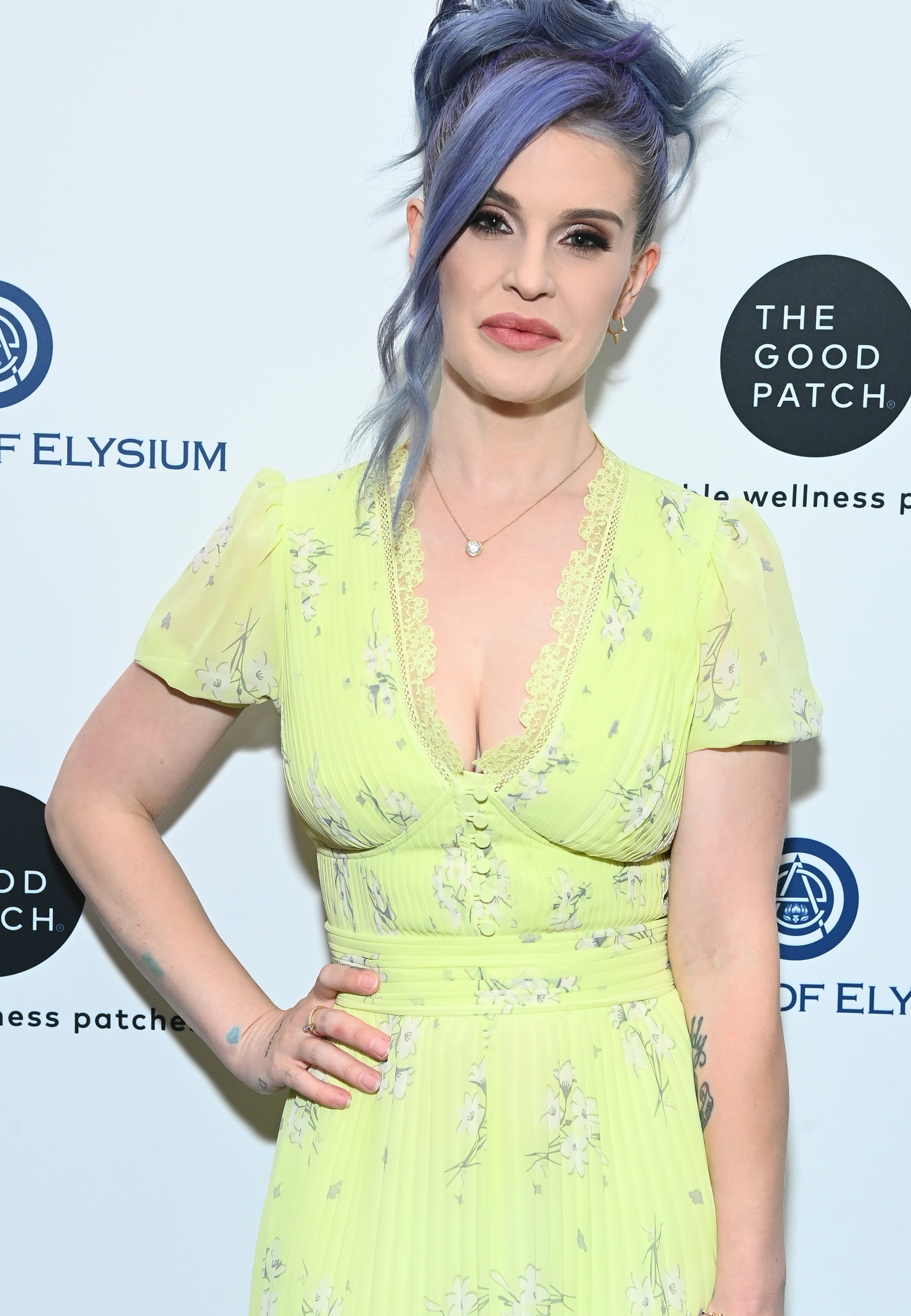 Woman with blue hair styled up, wearing a light yellow, floral dress, at The Art of Elysium event