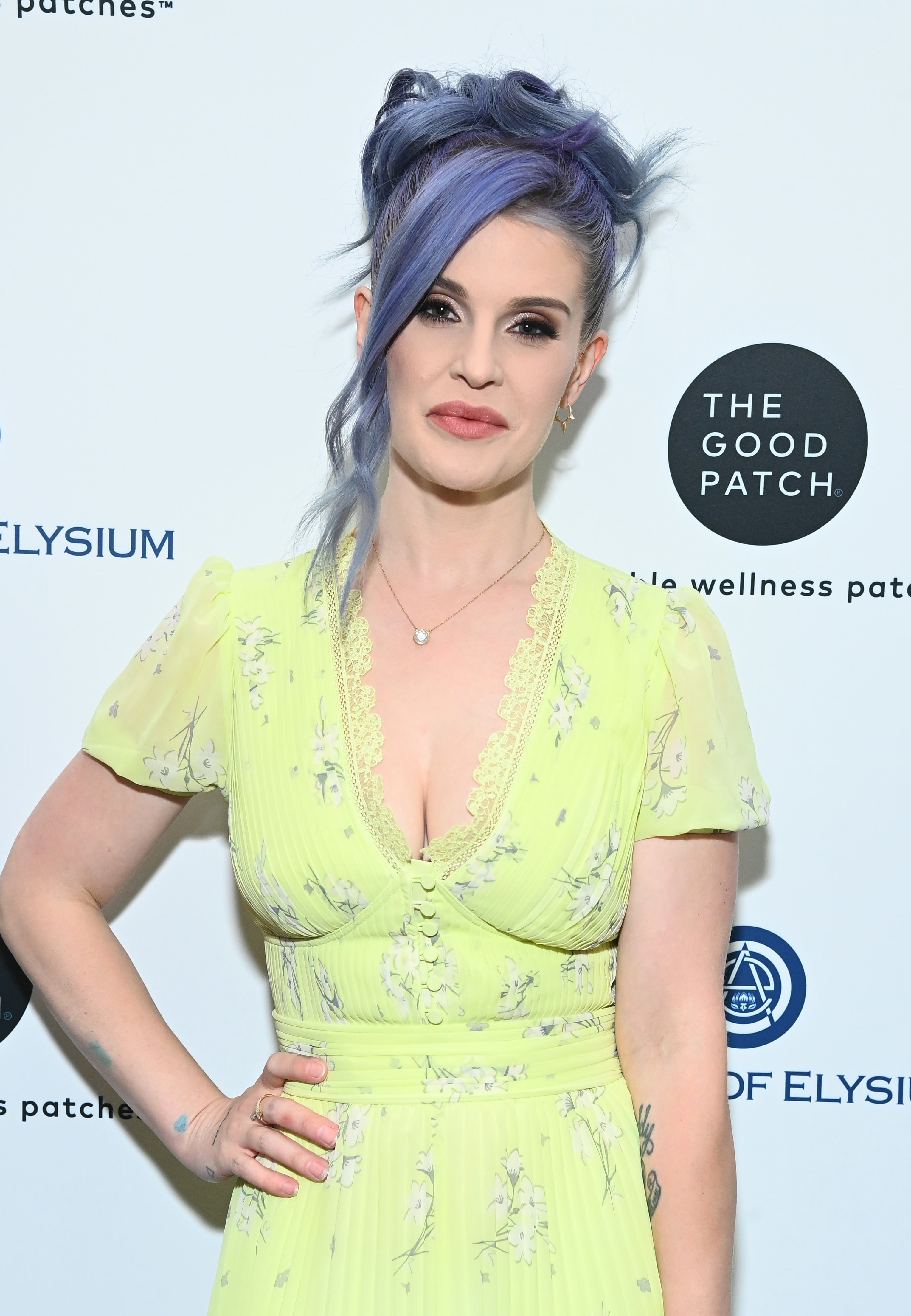 Woman with blue hair styled up, wearing a light yellow, floral dress, at The Art of Elysium event