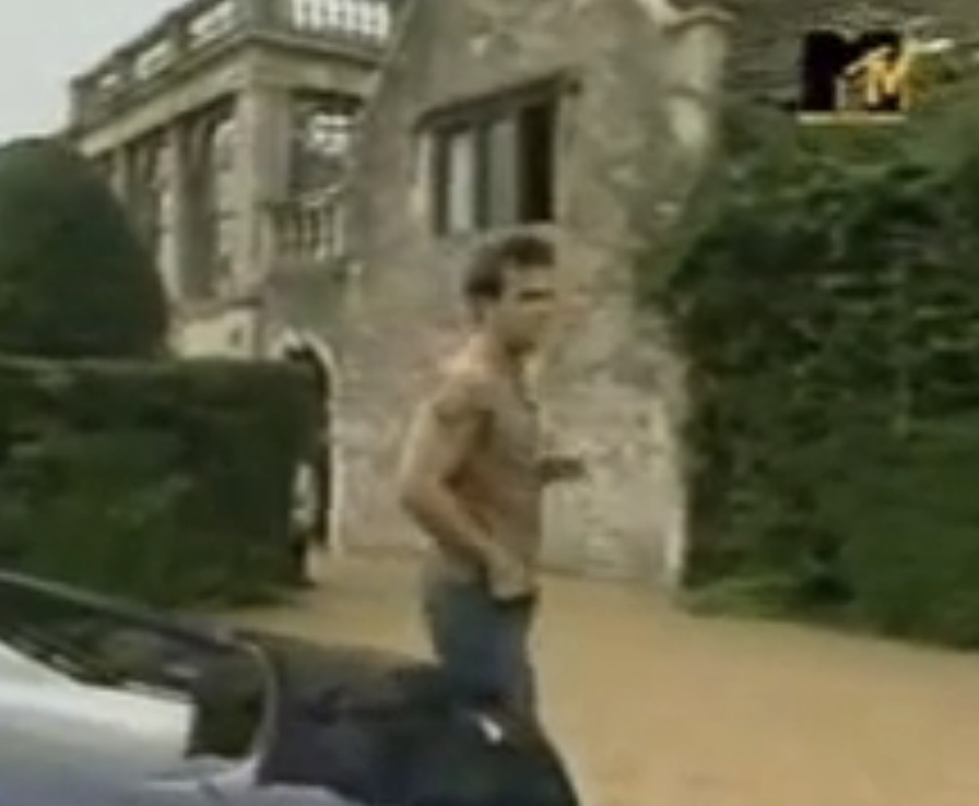 Robbie stands by a car outside a stately home on MTV Cribs UK