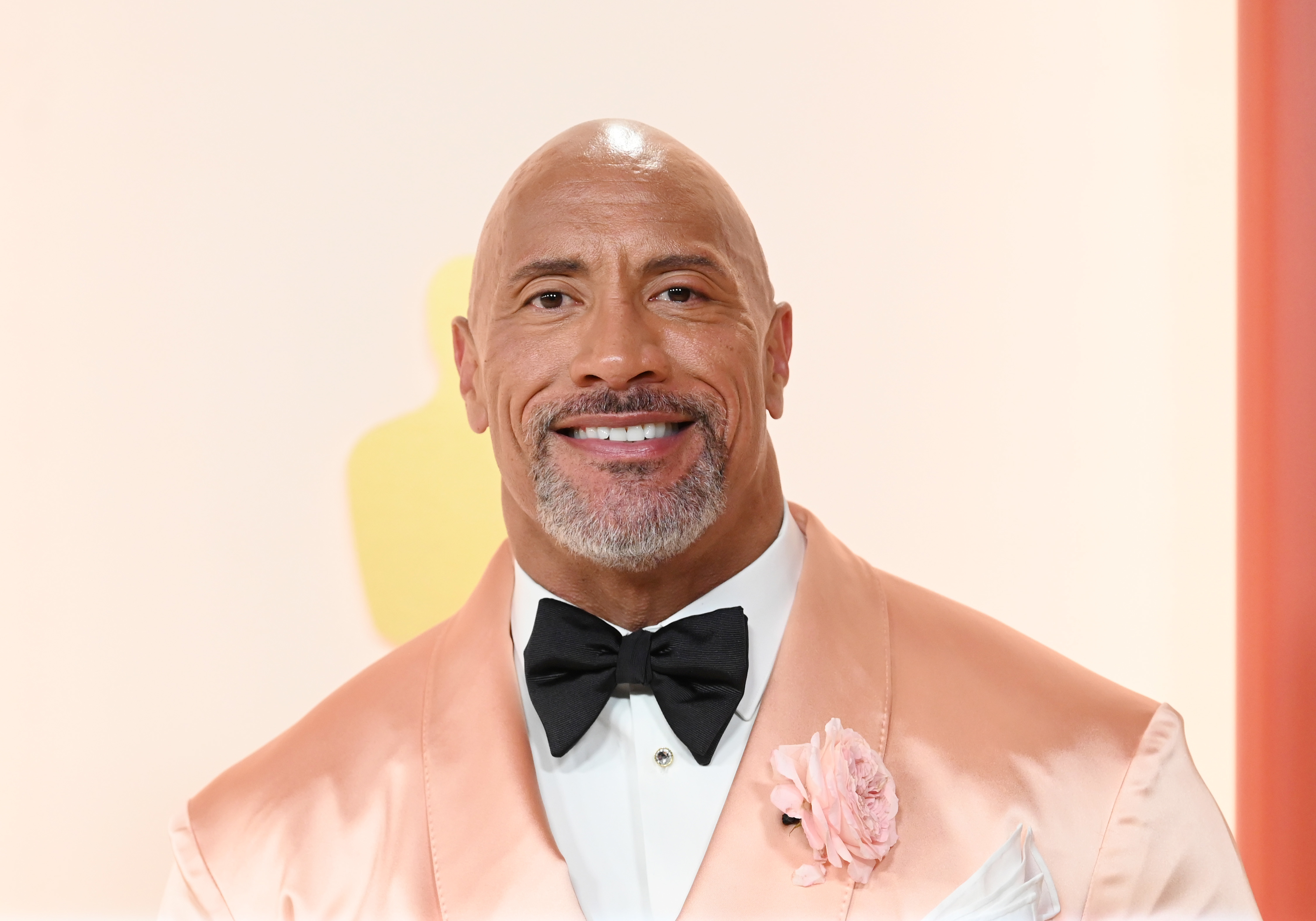 Dwayne in formal attire with a satin tuxedo and flower boutonniere at an event