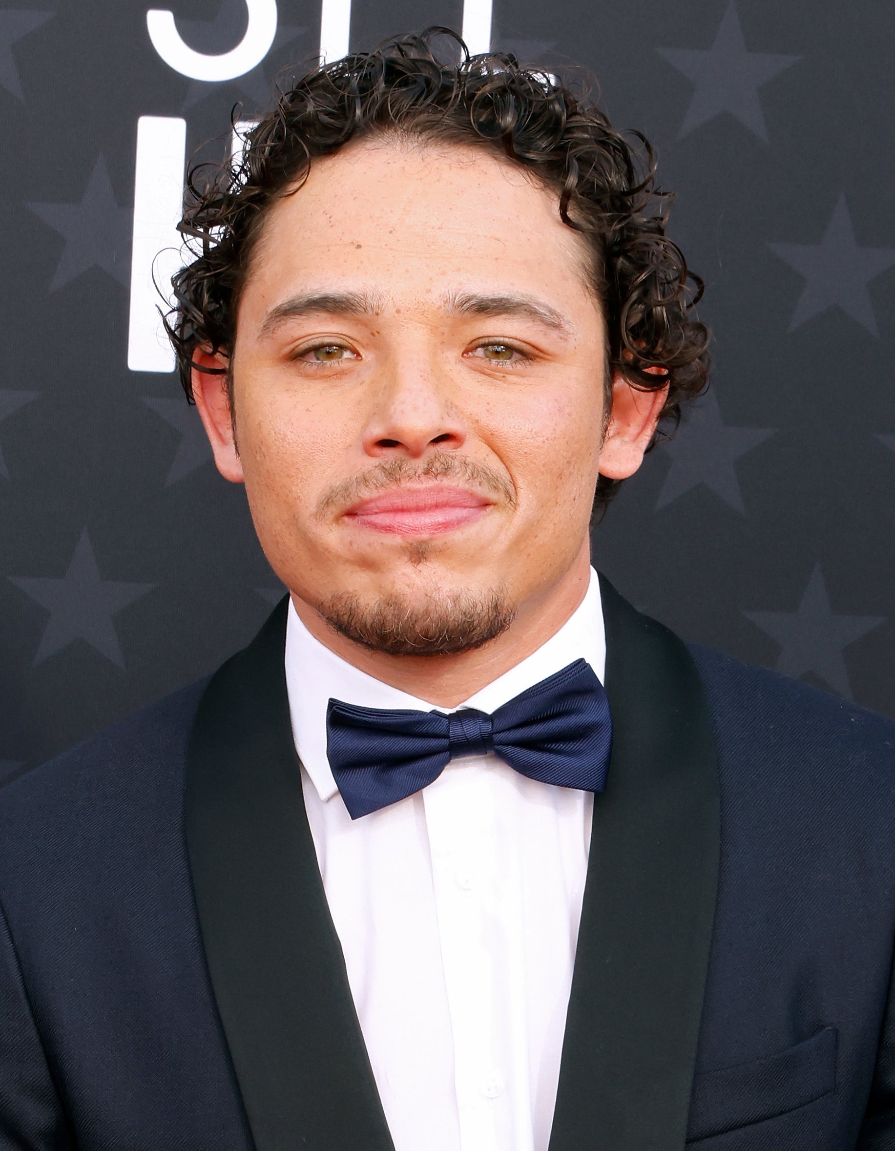 Anthony Ramos in a tuxedo and bow tie posing at an event