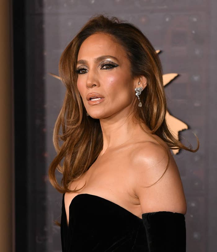 Jennifer Lopez on the red carpet wearing a strapless outfit and sparkling earrings, looking to the side