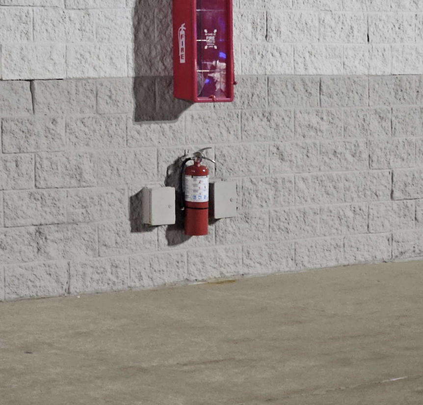 Fire extinguisher mounted on a wall next to an alarm box