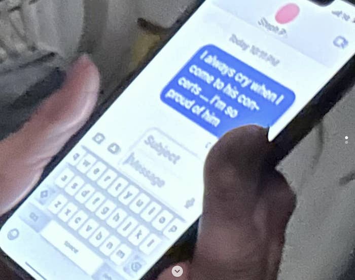 Close-up of a hand holding a phone with a blurred text conversation visible on the screen