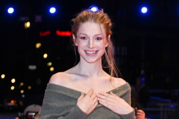 Hunter smiling on the red carpet in off-shoulder dress, smiling with hands crossed over chest