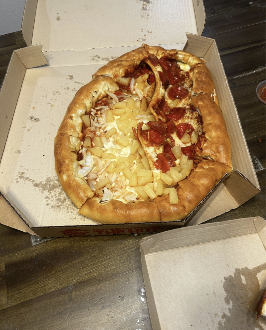 Pizza with a variety of toppings that's been smushed in an open box
