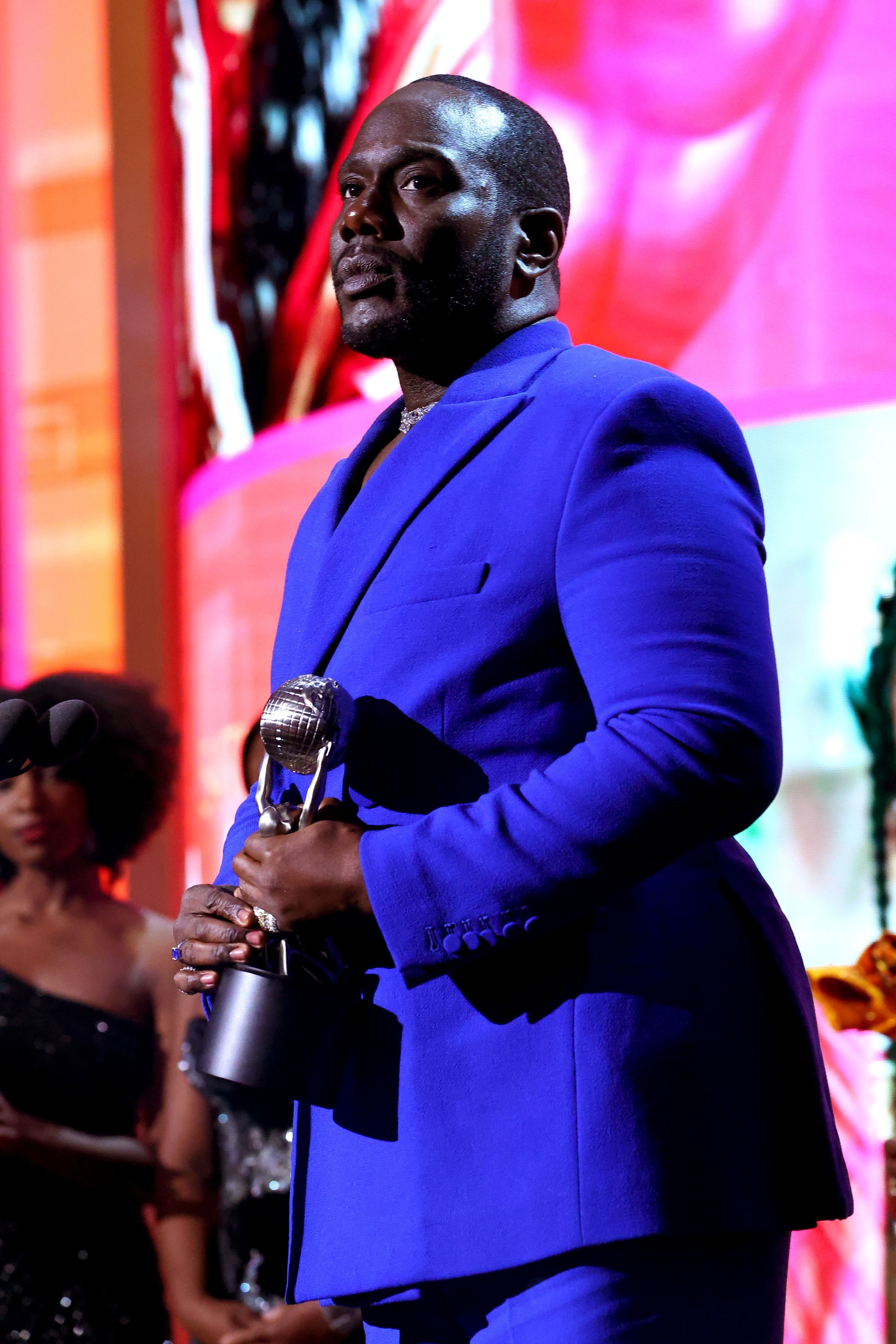 Michael Jordan in a tailored suit, holding an award onstage