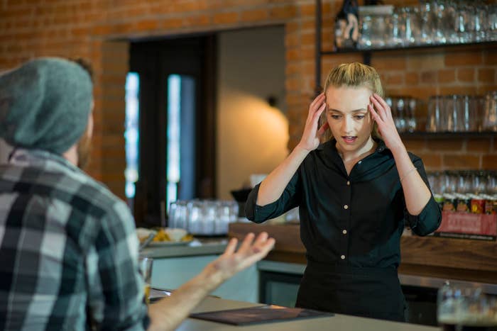 Server in a black shirt appears stressed during a conversation with a customer