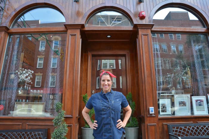 Jen Royle standing in front of Table&#x27;s entrance with hands on hips, smiling, wearing a denim dress and red headband