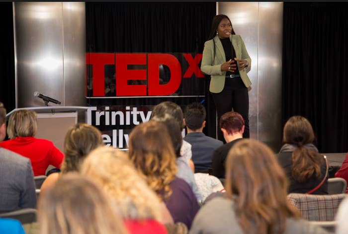 Speaker presenting at TEDx event, audience in foreground, TEDx logo in the background