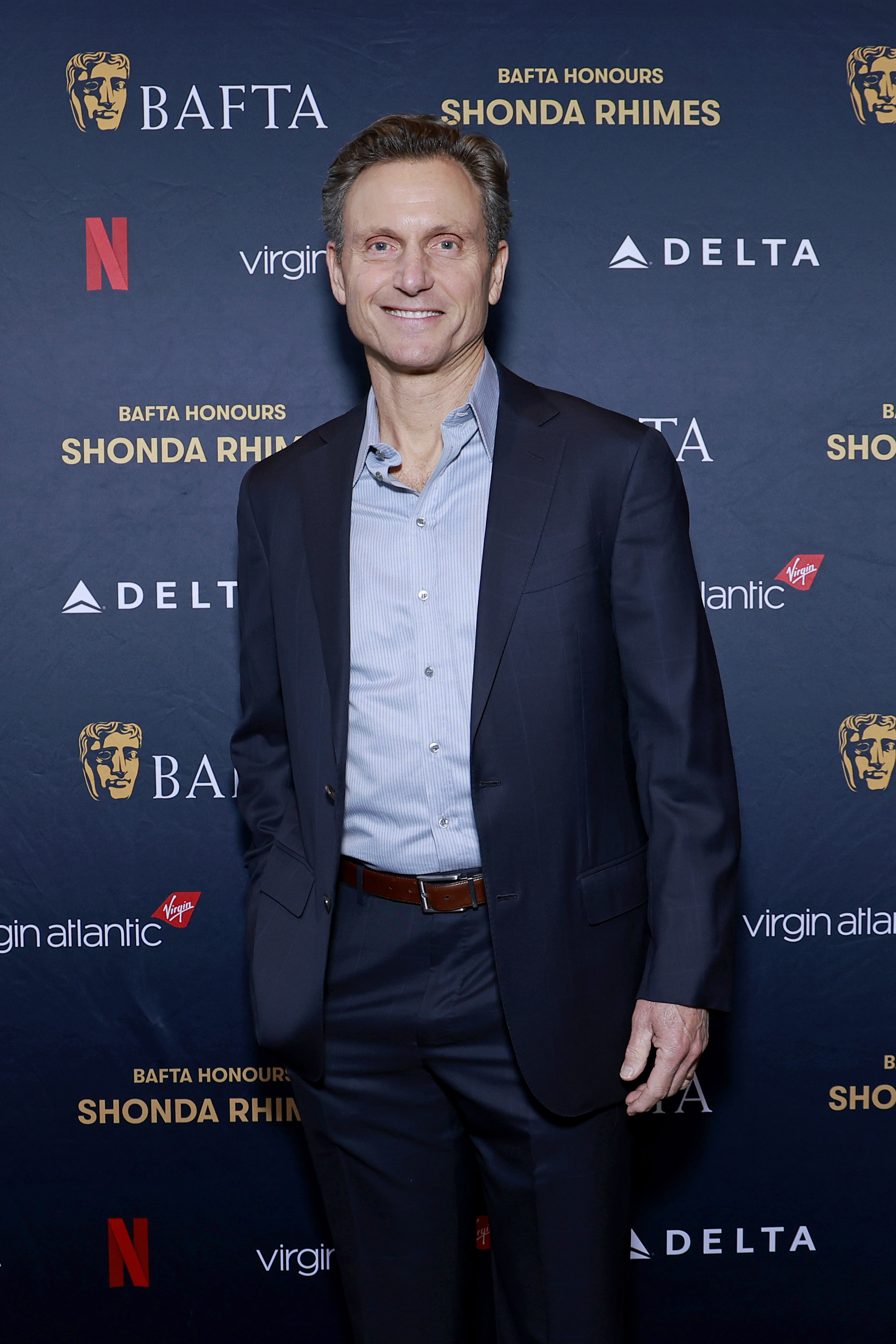Tony Goldwyn in a suit and open-collar shirt posing at the BAFTA event
