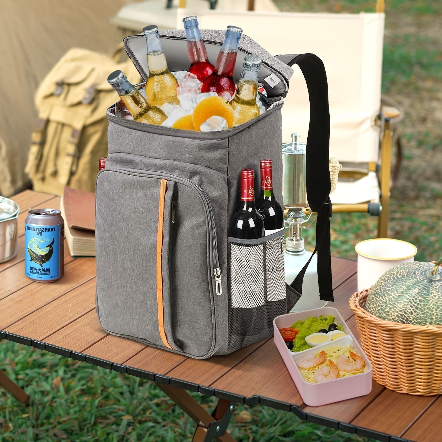 Insulated backpack cooler filled with various beverages and food, set on a table at an outdoor picnic. Perfect for on-the-go refreshment