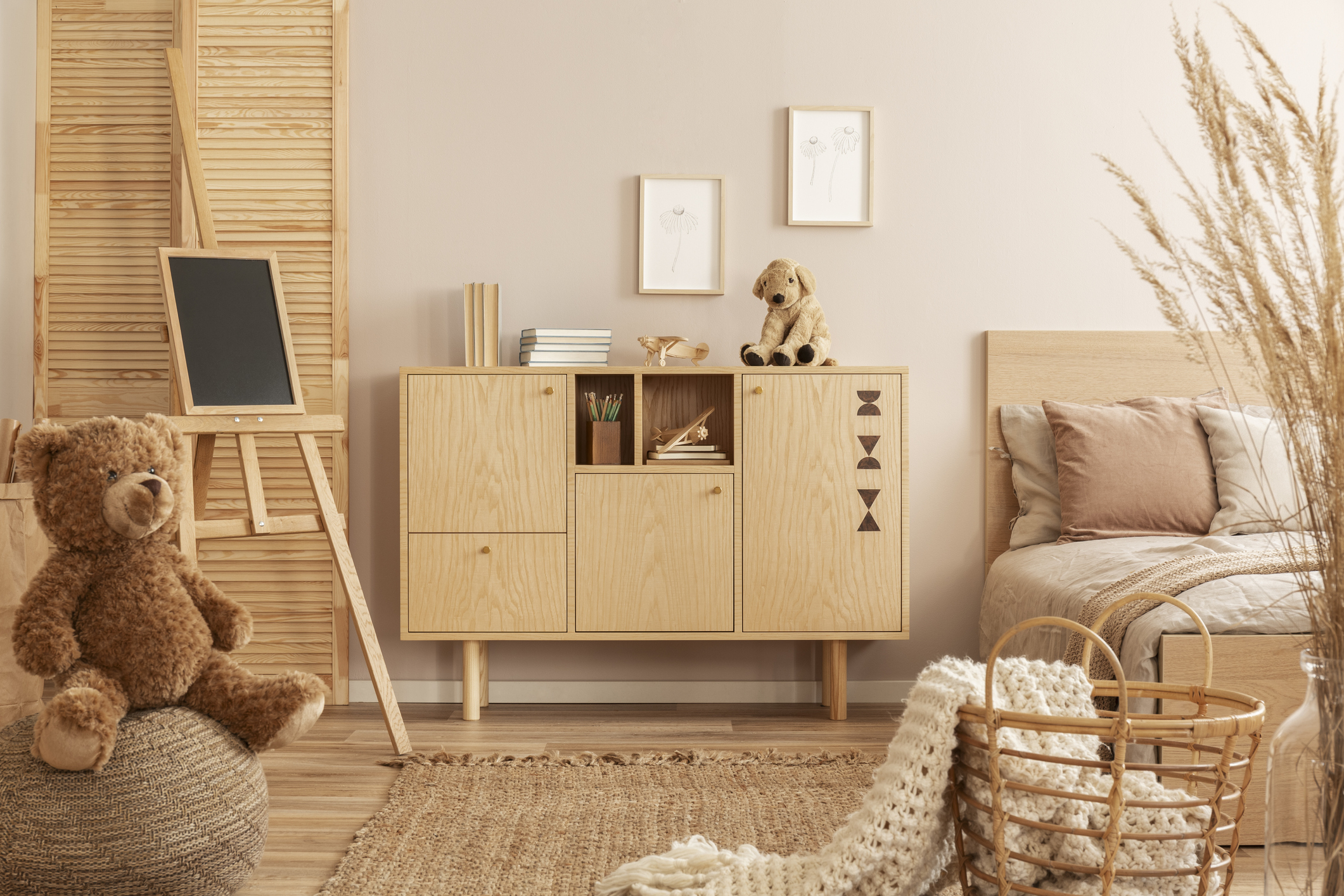 Cozy corner of a room with a wooden cabinet, soft toys, art easel, and cushioned seat with decor