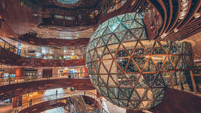 Large spherical geometric sculpture inside a multi-level shopping center
