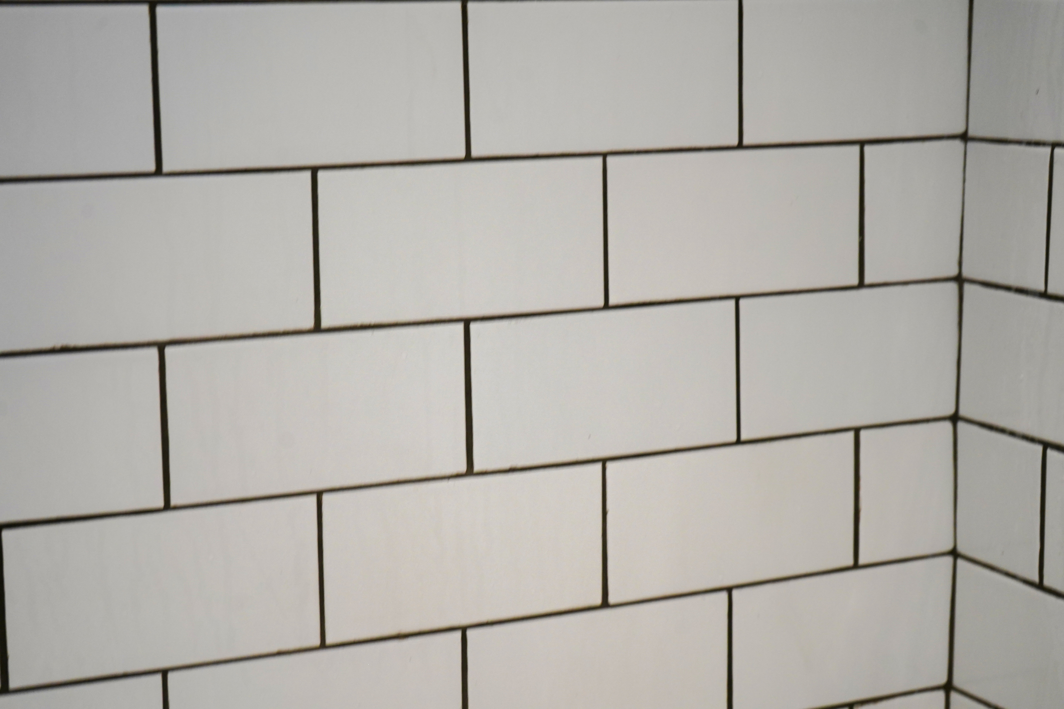 White subway tiles arranged in an offset pattern on a wall