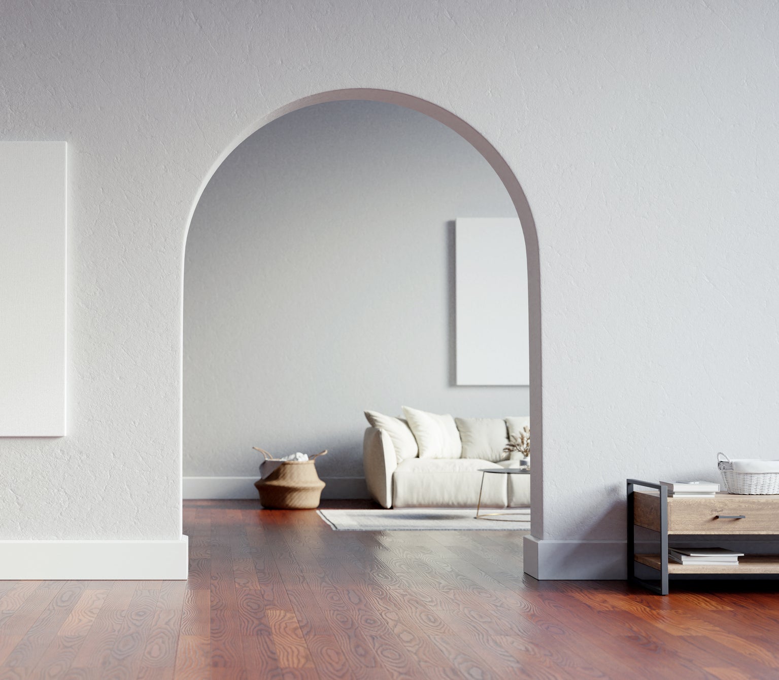 A minimalist room with an empty picture frame on the wall and a simple furnished living area through an archway