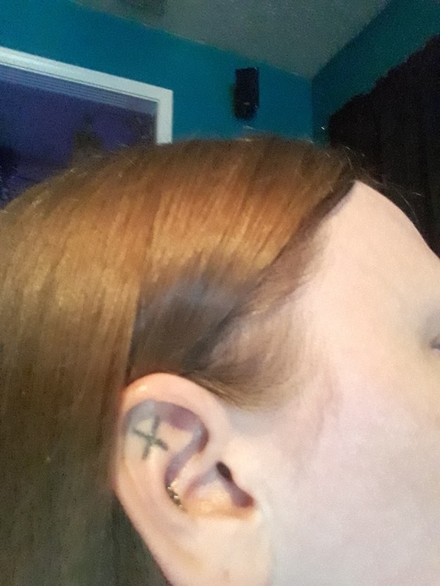 Person showing off a star tattoo behind their ear