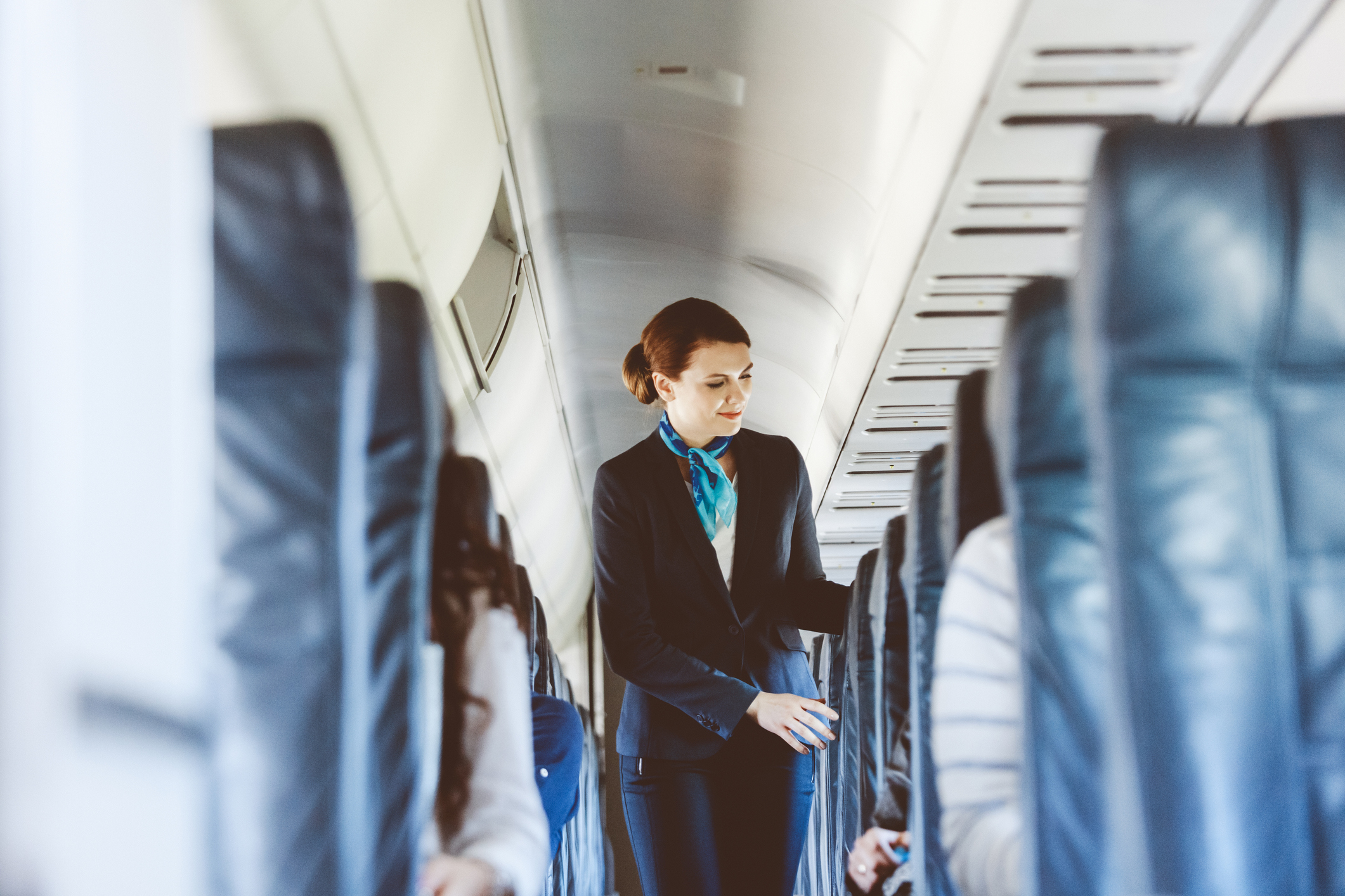 Flight attendant walking down the aisle of an airplane, checking on passengers