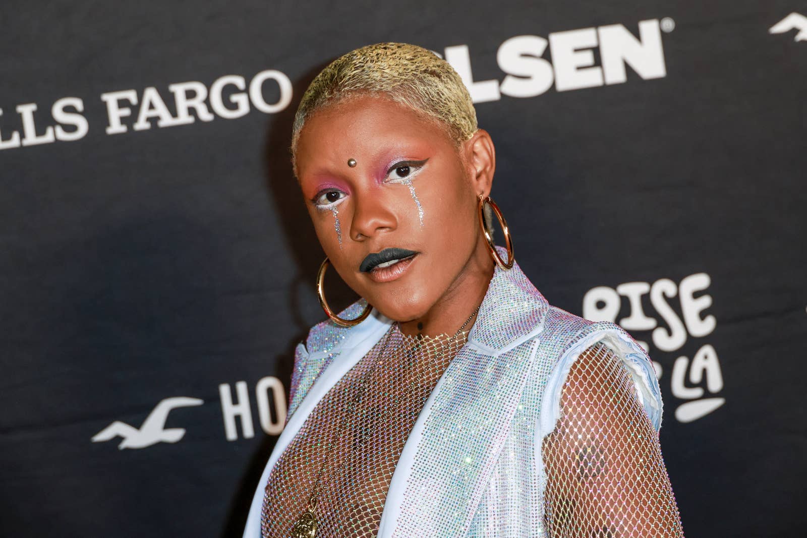 INIKO in a sequined outfit and bold makeup poses at an event