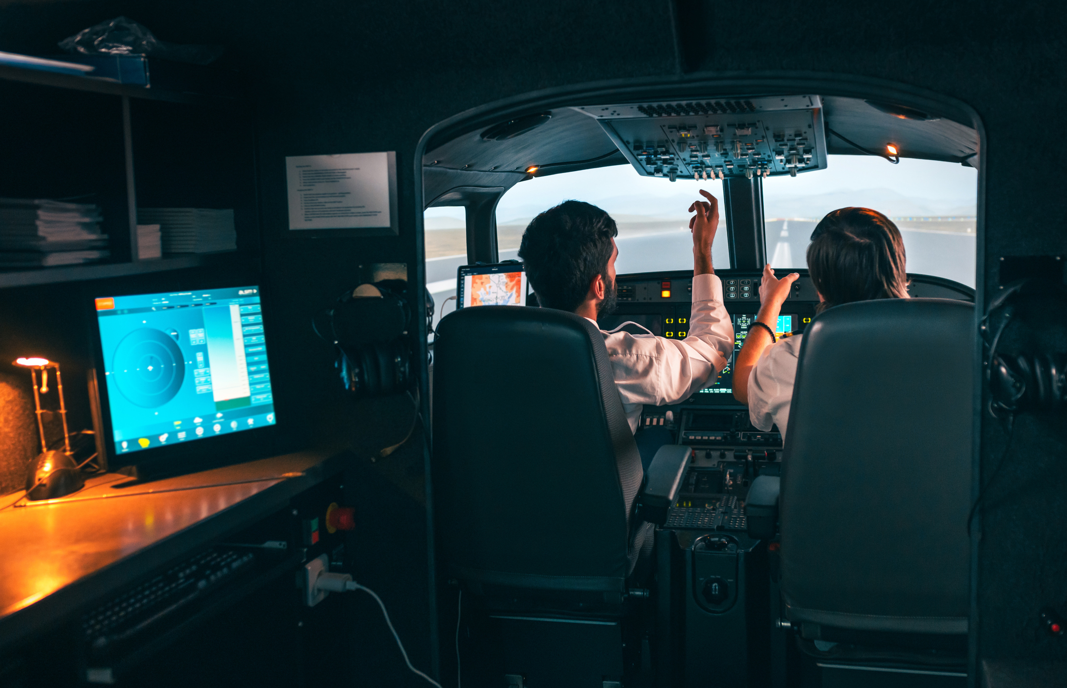 Two pilots operating controls in an airplane cockpit during a flight