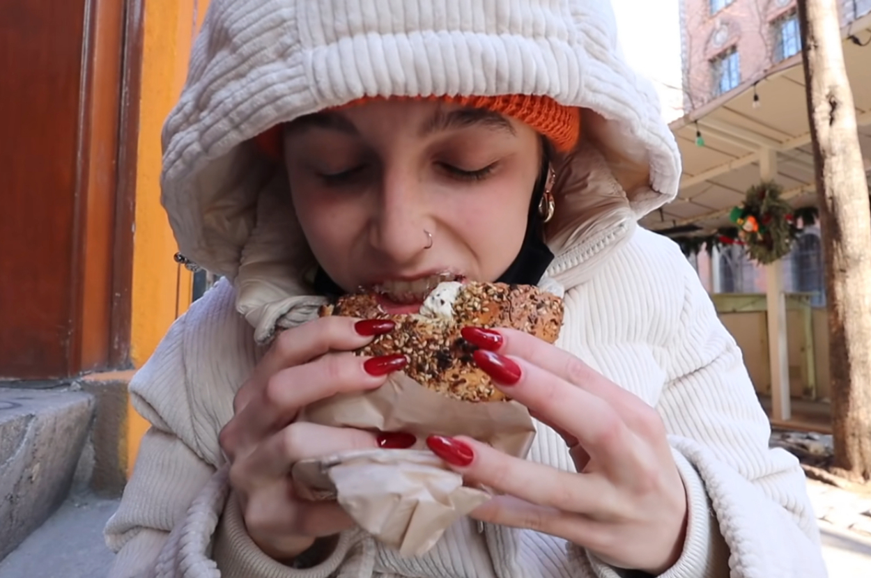 Emma Chamberlain eating a bagel with cream cheese
