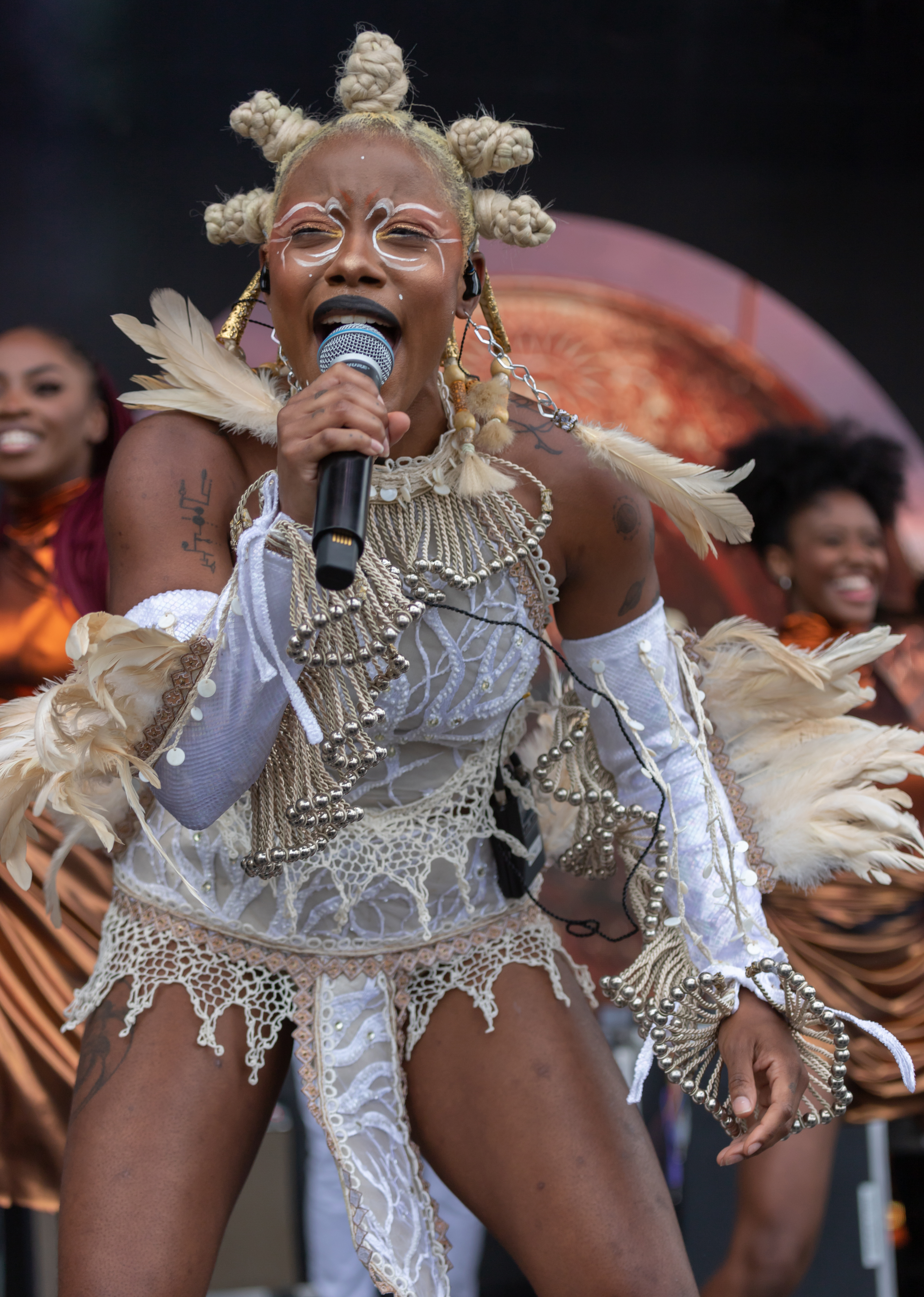INIKO in an ornate costume performing on stage with backup singers in the background