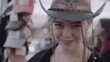 Mujer sonriendo con sombrero de vaquero en un entorno interior