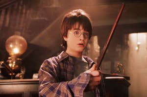 harry potter holds a wand and looks shocked