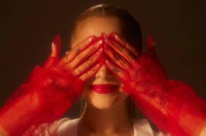 Ariana Grande with red gloves covering her eyes.