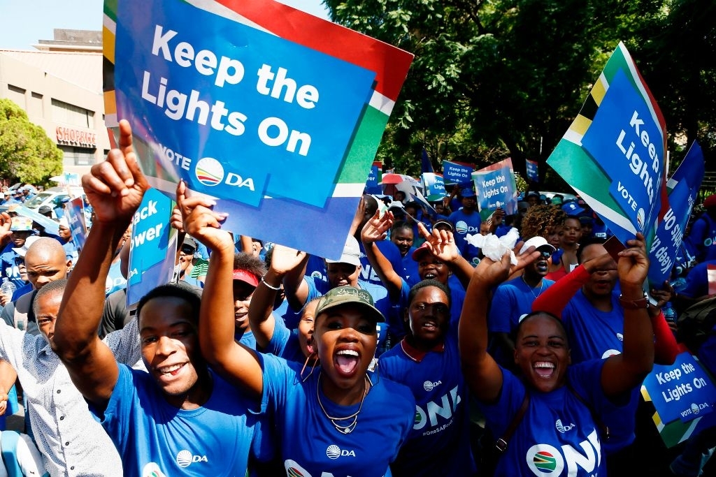 Crowd with signs reads &quot;Keep the Lights On&quot; and &quot;Vote DA&quot;, showing support for a political campaign