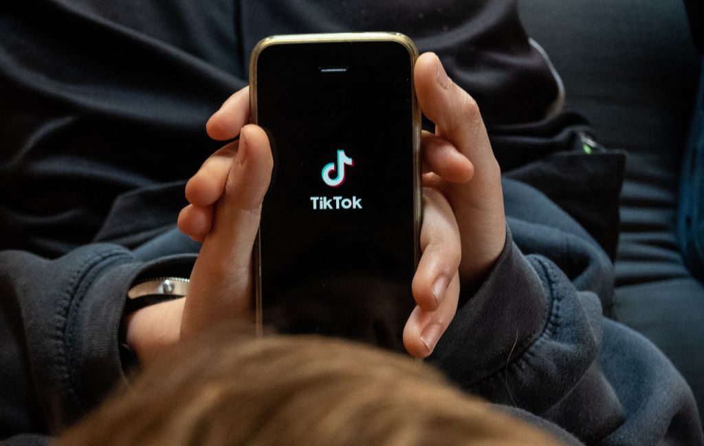 Person holding smartphone with TikTok logo on screen