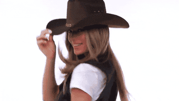 Mujer sonriente con sombrero vaquero y camiseta sin identificar