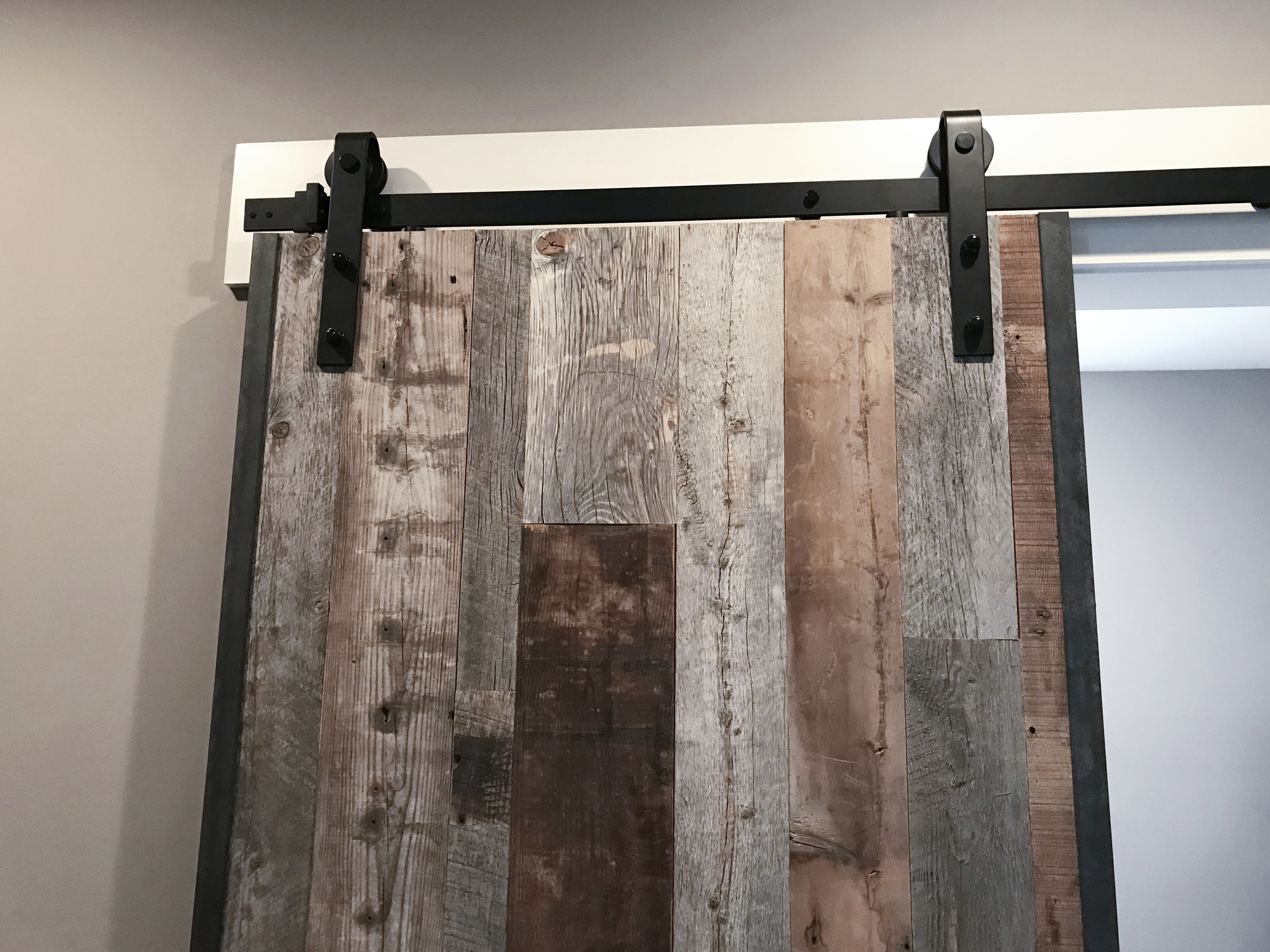 A rustic wooden barn door mounted on a sliding track above a doorway