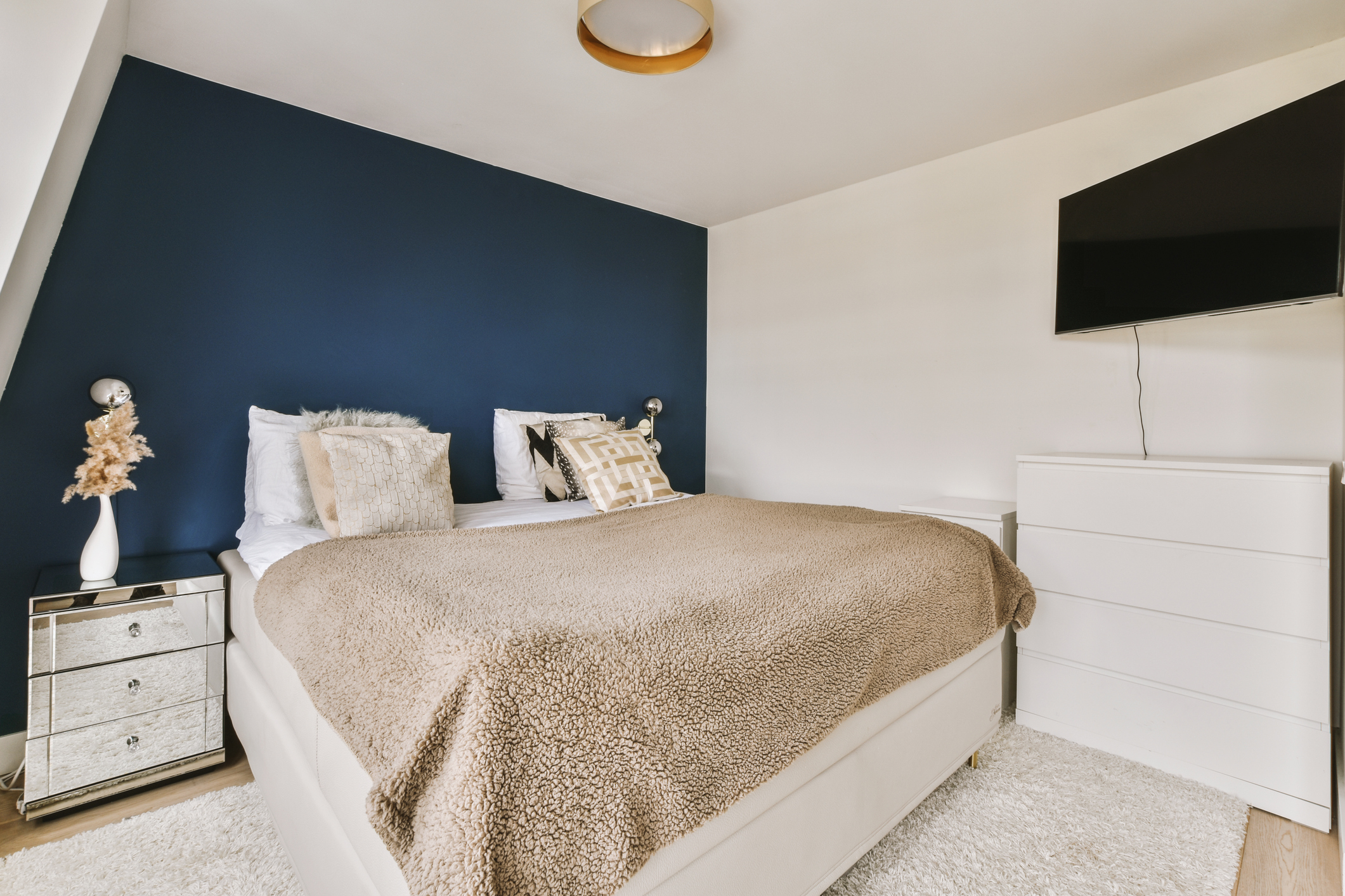 Bedroom with a bed, nightstands, and TV, featuring a prominent navy accent wall