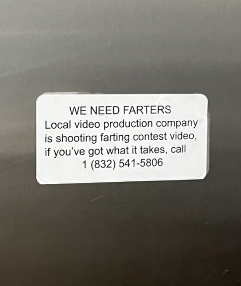 Sticker on a surface with text from a &quot;local video production company&quot; promoting a local farting contest and a phone number for contact