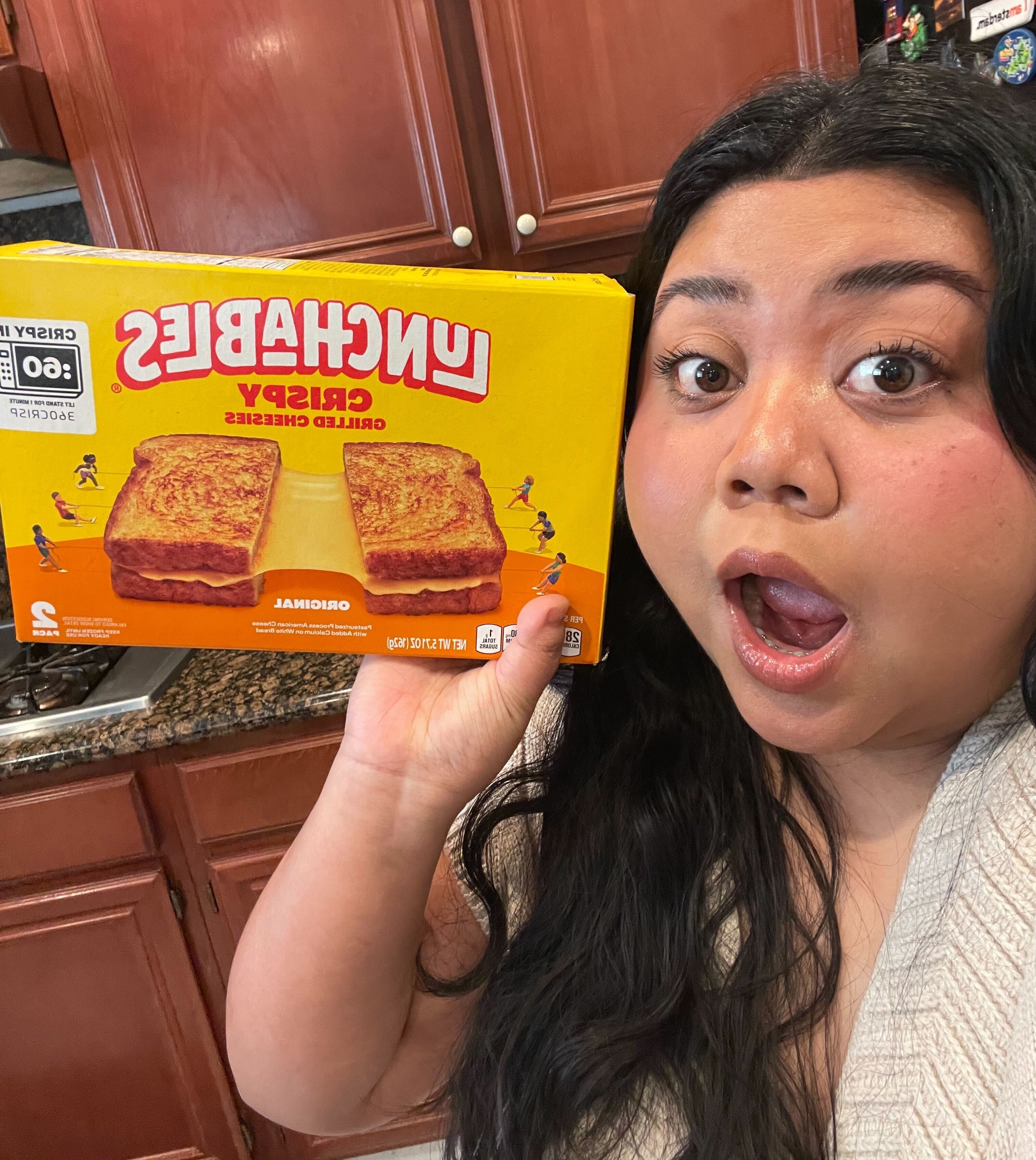 The author is holding a box of Lunchables Grilled Cheesies with a surprised expression