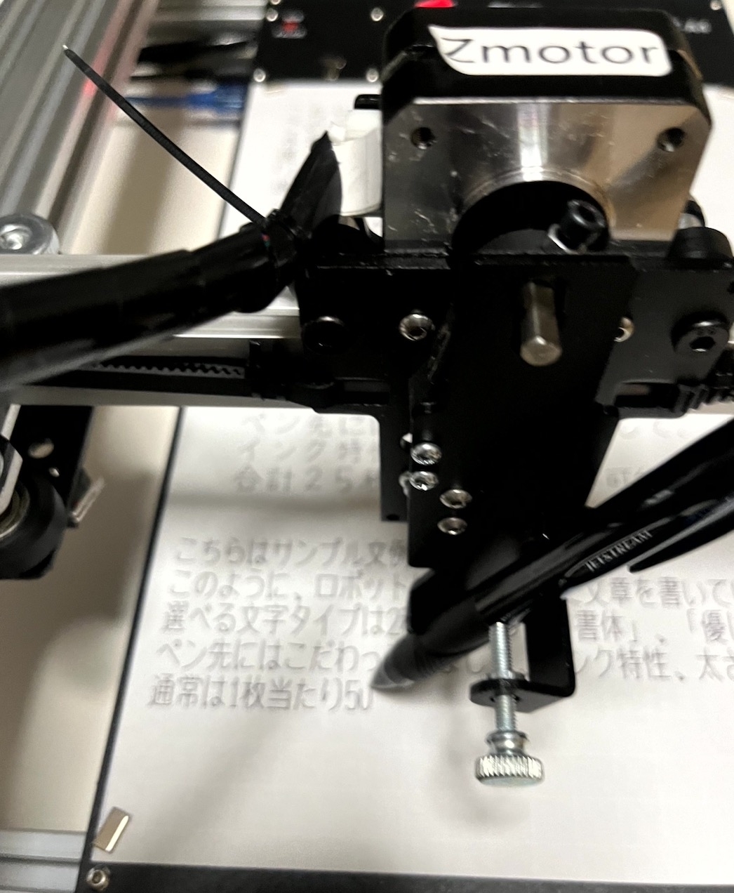 手書きの文章を自動筆記機械が書いている様子。