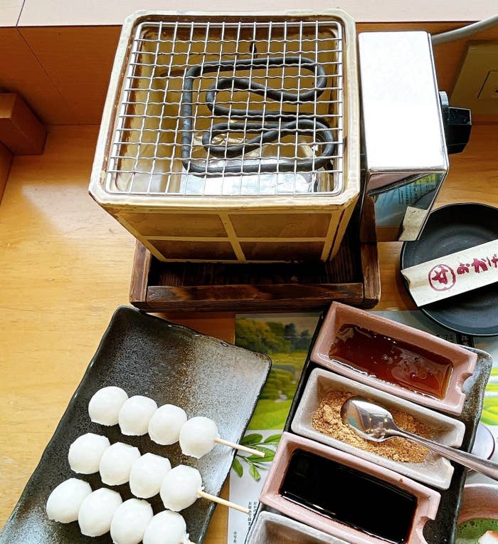 焼き網の上に置かれた焼肉用コンロ、丸いおにぎり、3種のたれが入った器がテーブルに並んでいる。